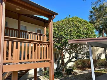 Inviting condo exterior featuring a covered walkway, mature landscaping, and dedicated covered parking at 4937 Marine Pkwy # 201, New Port Richey, FL 34652