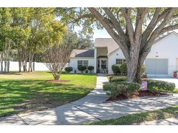 Well-maintained front yard with lush green grass, mature trees, and a neatly landscaped garden at 11526 Forest Run Ct, Port Richey, FL 34668