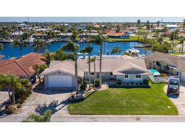 Waterfront home with lush landscaping, tile roof, and private boat dock on a sunny day at 3616 Harborview Ct, New Port Richey, FL 34652