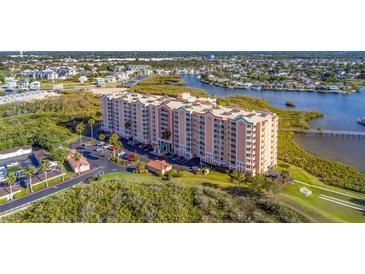 An aerial view of a pink waterfront condominium building with lovely landscaping and views of the bay at 4516 Seagull Dr # 408, New Port Richey, FL 34652