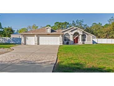 Charming single-story home featuring a three-car garage, arched windows, and a well-manicured front lawn at 13045 Marbled Godwit Rd, Weeki Wachee, FL 34614