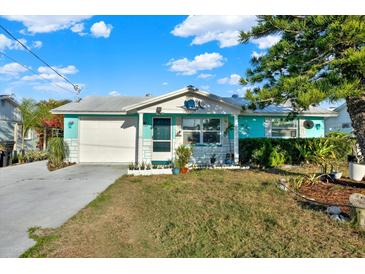 Charming home featuring a colorful exterior, white garage door, and well-manicured landscaping at 13906 Barnard Ave, Hudson, FL 34667