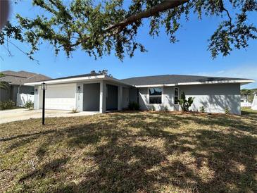 Charming single story home with a well-manicured front yard and a two-car garage under a clear blue sky at 1713 Walden Ct, Englewood, FL 34224