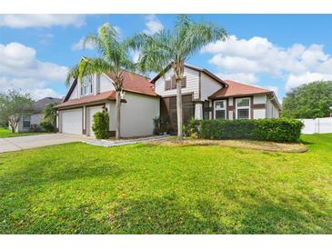 Well-maintained two-story home with lush green lawn and tropical landscaping creating curb appeal at 5737 Wynstone Ln, Zephyrhills, FL 33541