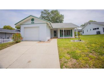 Charming single-story home with a well-maintained lawn, complemented by vibrant landscaping at 8121 Casuarina Dr, Port Richey, FL 34668
