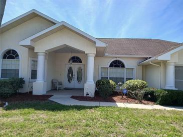 Charming single-story home featuring a beautiful front entrance with white columns and a well-manicured lawn at 8630 Ne Coral Creek Loop, Hudson, FL 34667