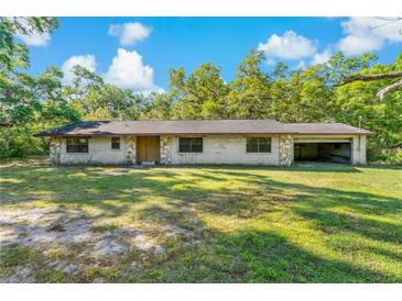 Charming single-story home with stone accents and an attached open garage, set against a lush, treed backdrop at 11423 Ennis Sheard Rd, Seffner, FL 33584