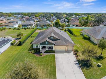 Expansive aerial view of a home with lush green lawns, mature trees, and a three-car garage in a lovely neighborhood at 1155 Buckhurst Dr, Spring Hill, FL 34609
