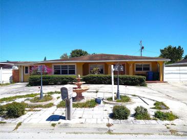 Ranch-style home featuring a circular driveway, water fountain, mature shrubbery, and secure mailbox at 4607 N Saint Vincent St, Tampa, FL 33614