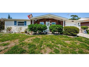 Charming home with brick accents, complemented by a well-manicured front yard, shrubs, and a vibrant flag at 4107 Glissade Dr, New Port Richey, FL 34652
