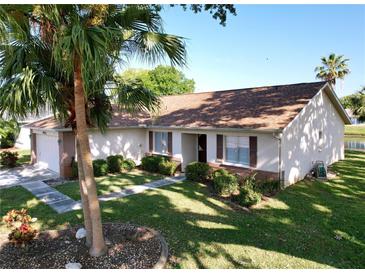 Charming single-story home with a well-maintained lawn and lush landscaping, including a mature palm tree at 4402 Grandwood Ln, New Port Richey, FL 34653