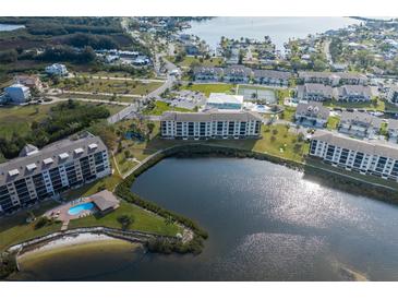 Aerial view of waterfront community featuring multiple buildings, a pool, a lake, and a beautiful landscape at 8251 Brent St # 918, Port Richey, FL 34668