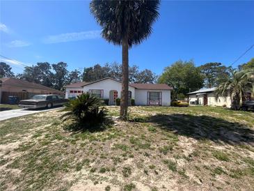 Quaint single-story home featuring a well-manicured front yard with mature trees and a long driveway at 2335 Canfield Dr, Spring Hill, FL 34609