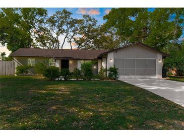 Charming single-story home with a well-manicured lawn, mature trees, and a two-car garage at 8364 Eldridge Rd, Spring Hill, FL 34608