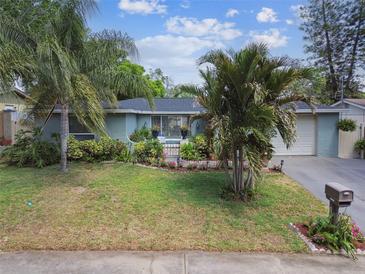 Charming single-story home with a well-manicured lawn, palm trees, and vibrant flower beds enhancing its curb appeal at 9040 Mark Twain Ln, Port Richey, FL 34668