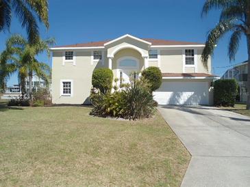 Two-story home with a manicured lawn, featuring a two-car garage, mature landscaping, and palm trees at 4009 Triggerfish Dr, Hernando Beach, FL 34607