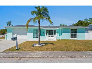 Charming one-story home featuring a well-maintained yard, light blue exterior, and a palm tree in the front at 7221 Westwind Dr, Port Richey, FL 34668