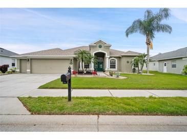 Charming single-story home featuring lush landscaping, palm trees, and a welcoming facade at 7511 Melogold Cir, Land O Lakes, FL 34637