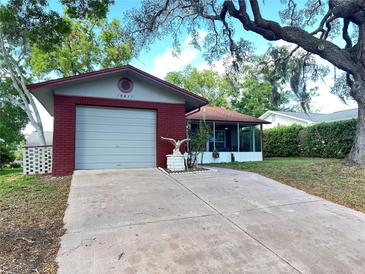 Charming home with a red brick facade, attached garage, and a screened-in porch at 10619 Mira Vista Dr, Port Richey, FL 34668
