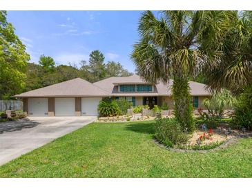 Charming single-story home with a three-car garage, a large manicured lawn, and mature landscaping at 6475 Laurel Oak Dr, Spring Hill, FL 34607