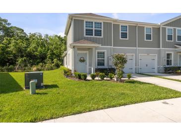 Charming townhome with well-manicured lawn and landscaping, featuring a one-car garage and neutral color scheme at 12214 Grizzly Ln, New Port Richey, FL 34654