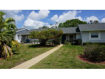 Charming home featuring a walkway leading to the entrance and lush, mature landscaping at 12371 Dearborn Dr, Hudson, FL 34667