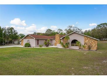 Charming single-story home featuring stucco exterior with stone accents, well-maintained lawn, and mature landscaping at 18216 Monteverde Dr, Spring Hill, FL 34610