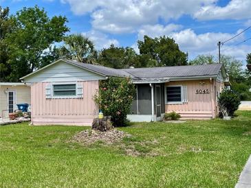 Charming pink single-story home featuring a screened porch and well-maintained lawn at 6045 Colony Cir, Weeki Wachee, FL 34607