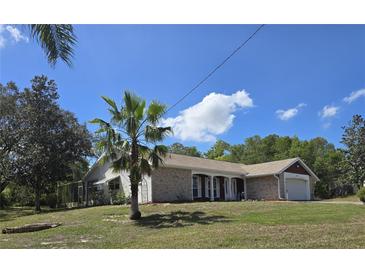 Single-story home boasts a brick facade, attached garage, and a well-manicured lawn with mature trees at 6516 Hillview Rd, Spring Hill, FL 34606