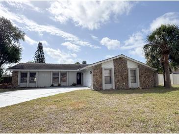 Charming single-story home featuring a stone facade, well-maintained lawn, and a paved driveway at 7026 Whitethorn Ct, Port Richey, FL 34668