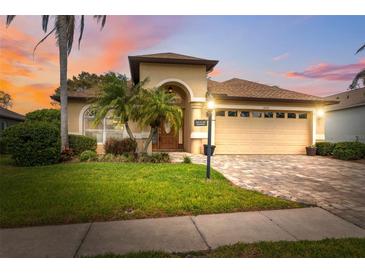 Charming single-story home with lush landscaping, paver driveway, and a two-car garage at sunset at 11631 Wayside Willow Ct, Hudson, FL 34667