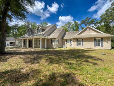 Charming home featuring a spacious front yard, inviting porch, and classic architectural details under a partly cloudy sky at 18308 Valor Path, Brooksville, FL 34604