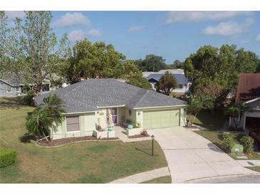 Well-maintained single-Gathering home featuring a manicured lawn, mature trees, and a two-car garage at 4647 Gazebo Ct, New Port Richey, FL 34655