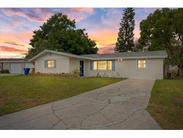 Charming single-story home with a well-maintained lawn and a cracked concrete driveway under a colorful sunset sky at 6335 Kings Ct, New Port Richey, FL 34653