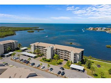 Aerial view of a beachfront condo building, showcasing its architecture and waterfront location with adjacent parking at 8211 Brent St # 837, Port Richey, FL 34668