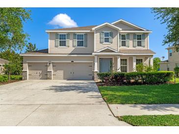 Inviting two-story home featuring a three-car garage, manicured lawn and charming curb appeal at 13619 Hunters Point St, Spring Hill, FL 34609