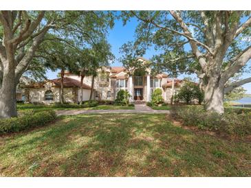 Stately two-story home featuring a lush front yard and a grand entrance framed by mature trees at 1473 Sail Harbor Cir, Tarpon Springs, FL 34689