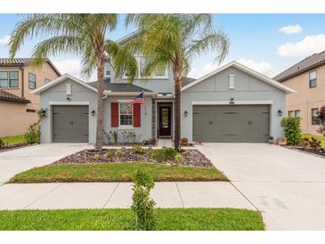 Beautiful two-story home with a three-car garage, well-manicured landscaping, and two palm trees at 1771 Whitewillow Dr, Wesley Chapel, FL 33543
