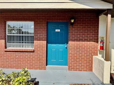 Inviting unit 203 with brick facade, a bright blue door and a conveniently located fire extinguisher at 24862 Us Highway 19 N # 203, Clearwater, FL 33763