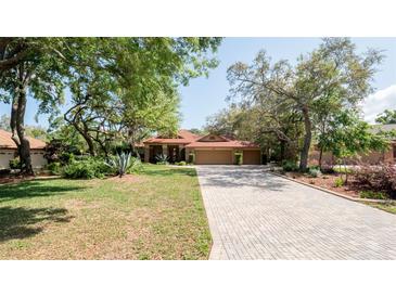 Charming single-story home featuring a brick driveway, mature trees, and beautiful landscaping at 4475 Rachel Blvd, Spring Hill, FL 34607