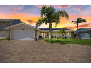 Charming home featuring a brick driveway, lush landscaping, solar panels and an attached two-car garage at 5033 Cabrilla Ct, New Port Richey, FL 34652