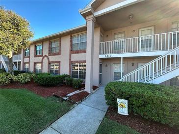 Inviting condo exterior features manicured landscaping, and a covered walkway leading to the entrance at 6440 Spring Flower Dr # 14, New Port Richey, FL 34653