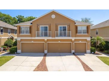 Two-story townhome featuring three garage doors and charming Juliette balconies on the second level at 7500 Red Mill Cir, New Port Richey, FL 34653