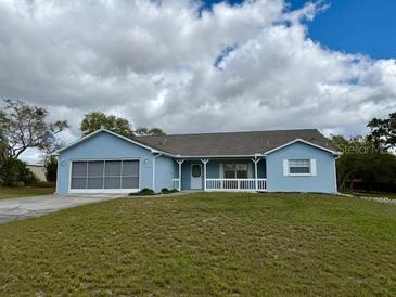 Charming single-story home featuring a light blue exterior, screened garage, and a covered front porch with white railings at 13377 Montour St, Brooksville, FL 34613
