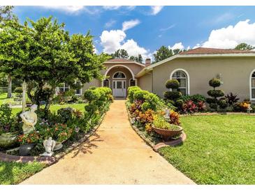 Charming home with a welcoming walkway, lush landscaping, and manicured lawn at 22106 Garmisch Way, Brooksville, FL 34601