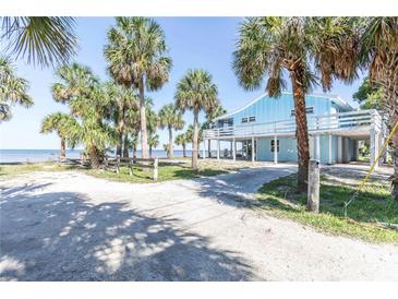 Charming beach house with elevated deck, surrounded by swaying palm trees and sandy beach access at 3461 Gum Dr, Weeki Wachee, FL 34607
