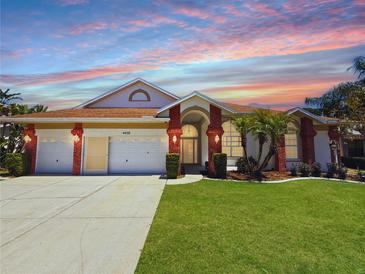Charming single-story home with a three-car garage, red brick accents, and a well-manicured lawn at 4450 Anaconda Dr, New Port Richey, FL 34655