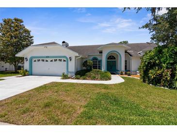 Charming single-story home with a well-manicured lawn, two-car garage, and a lovely blue trim at 473 Tournament Dr, Spring Hill, FL 34608