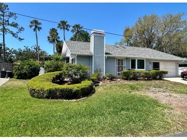 Charming single-story home featuring a well-manicured lawn and lush landscaping with palm trees and a winding walkway at 7444 Candlelight Ct, New Port Richey, FL 34652