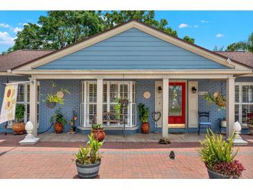 Charming home featuring a brick porch, vibrant red door, decorative plants, and a quaint window seat at 8516 Wooddrift Dr, Tampa, FL 33615